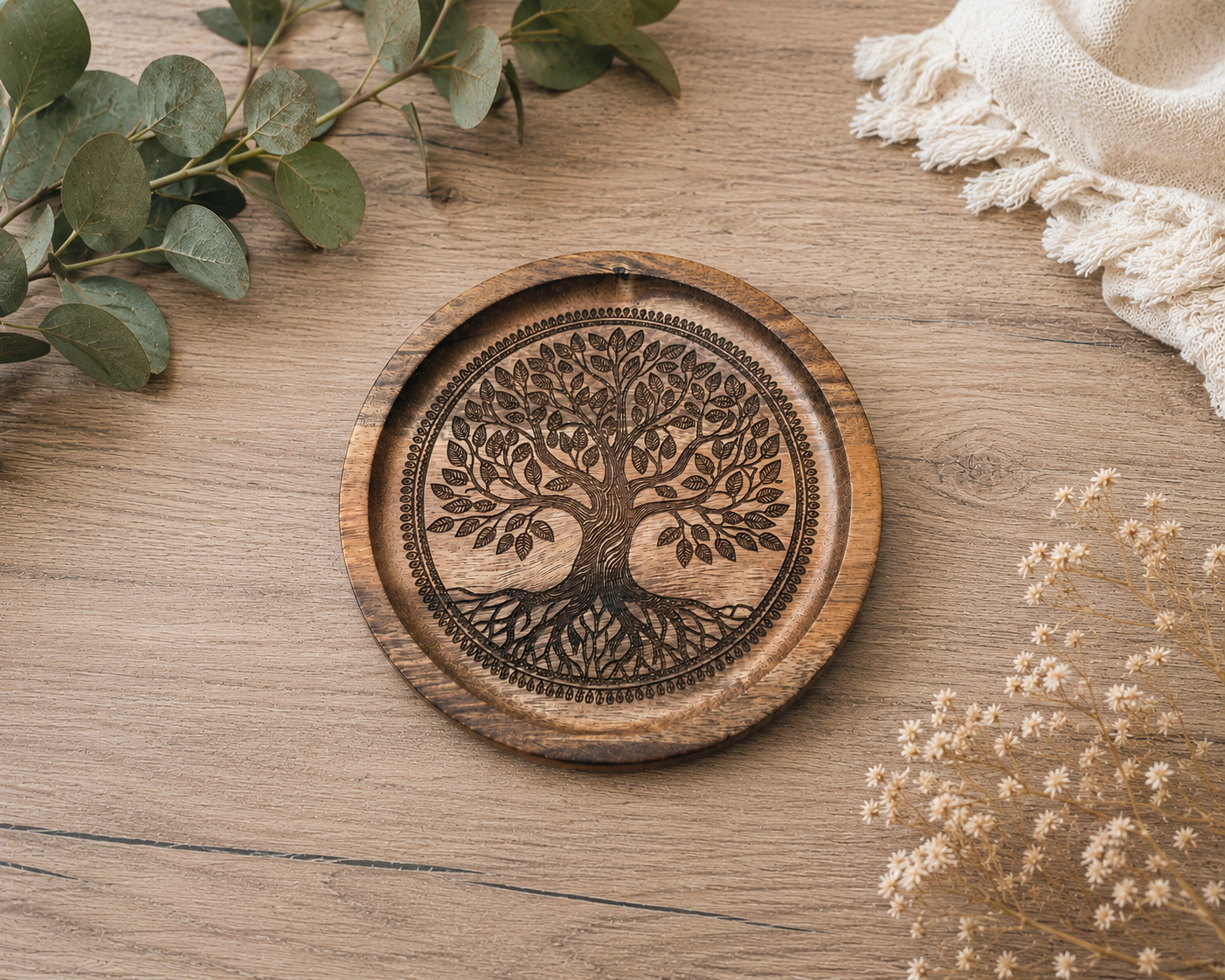 Plateau décoratif en bois gravé du motif Arbre de Vie, présenté en gros plan sur une table rustique avec une décoration végétale naturelle.