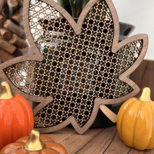 Décoration feuille d’automne en bois avec motif géométrique présentée dans une ambiance naturelle avec une plante verte