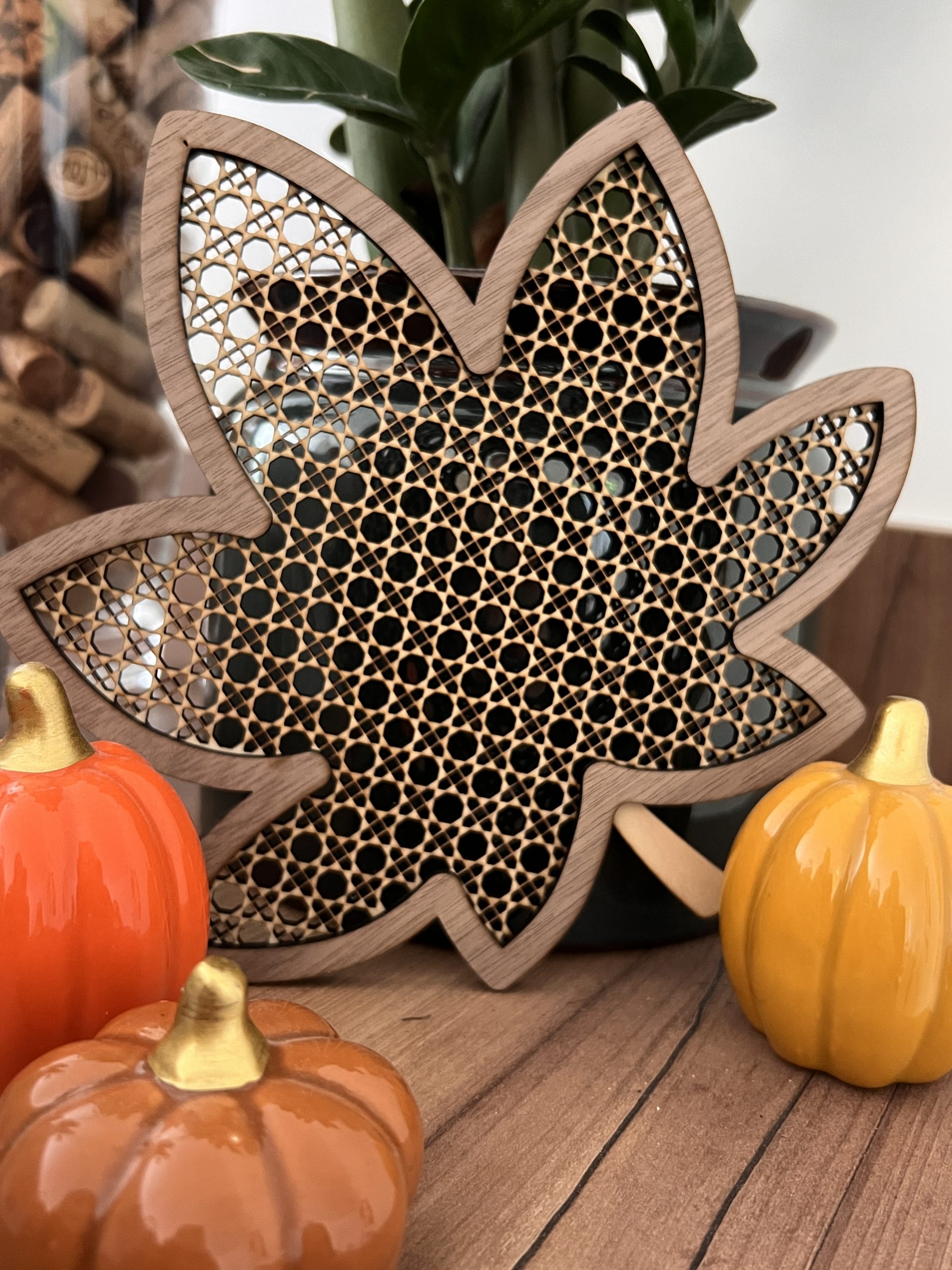 Décoration feuille d’automne en bois avec motif géométrique présentée dans une ambiance naturelle avec une plante verte